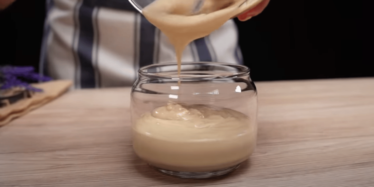 Glazen potje met zelfgemaakte haarboter op een houten tafel, omringd door verse rozemarijn, kruidnagels en flesjes met natuurlijke oliën – symbool voor natuurlijke haarverzorging en haargroei.