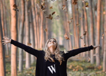 Een vrouw met rommelige haren en open armen in de wind – loslaten & vrijheid