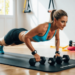 Persoon voert push-ups uit op een fitnessmat in de woonkamer, met dumbbells en weerstandsband in zicht – thuis je bovenlichaam trainen zonder sportschool.