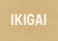 Minimalistische afbeelding met het woord 'IKIGAI' in grote witte letters op een beige achtergrond, symbool voor rust, eenvoud en zingeving na je 40e.